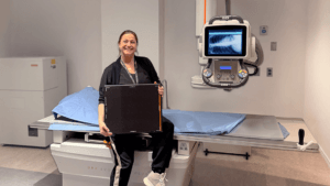 Jennifer, Charge Technologist, sitting on new X-ray unit at Bowmanville Hospital.