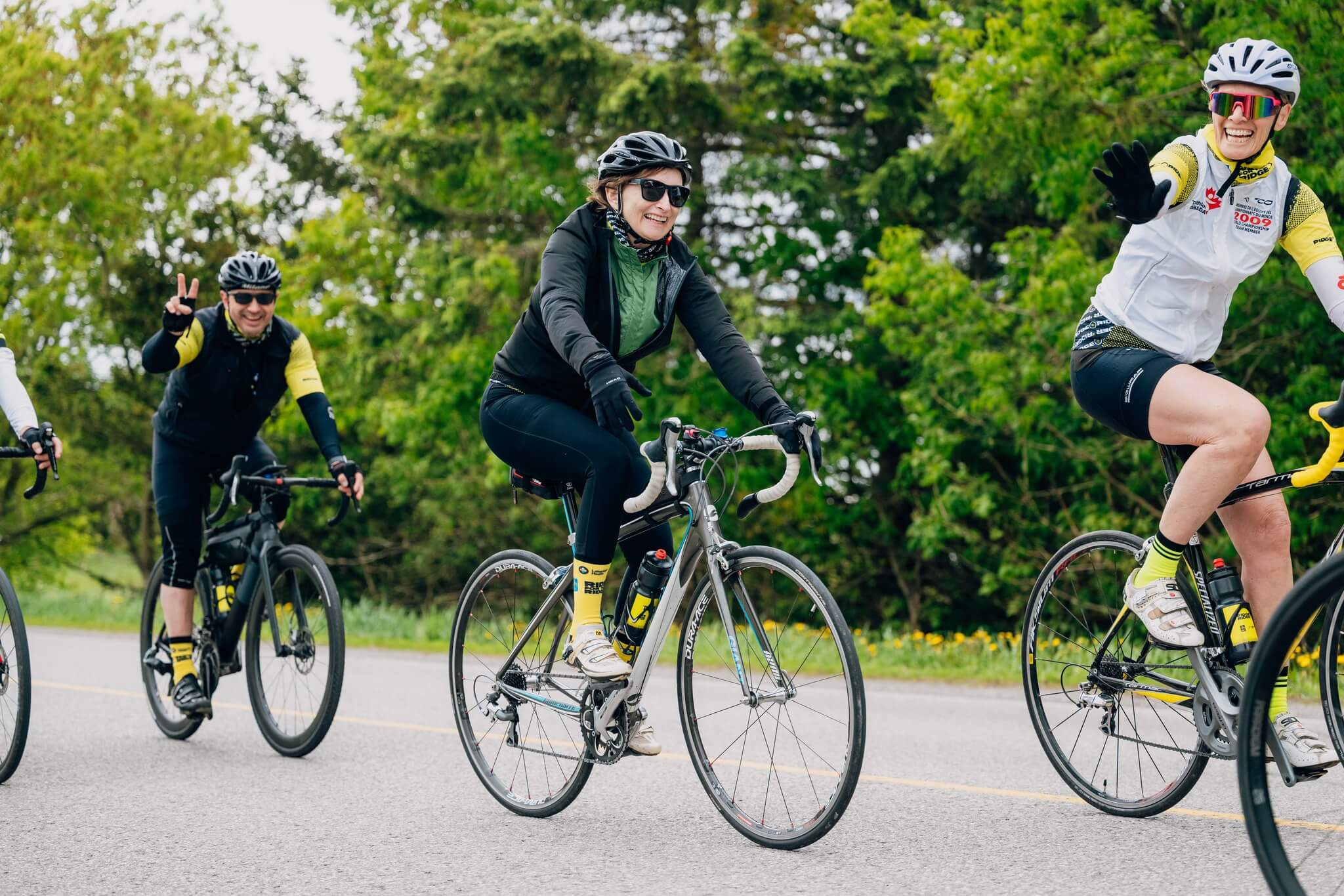 Three bike riders on a path with greenery in the background.