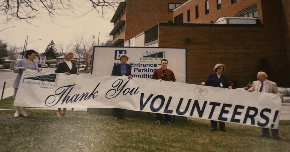 Six people standing outside of the Bowmanville Hospital with a sign that reads: "Thank You Volunteers."