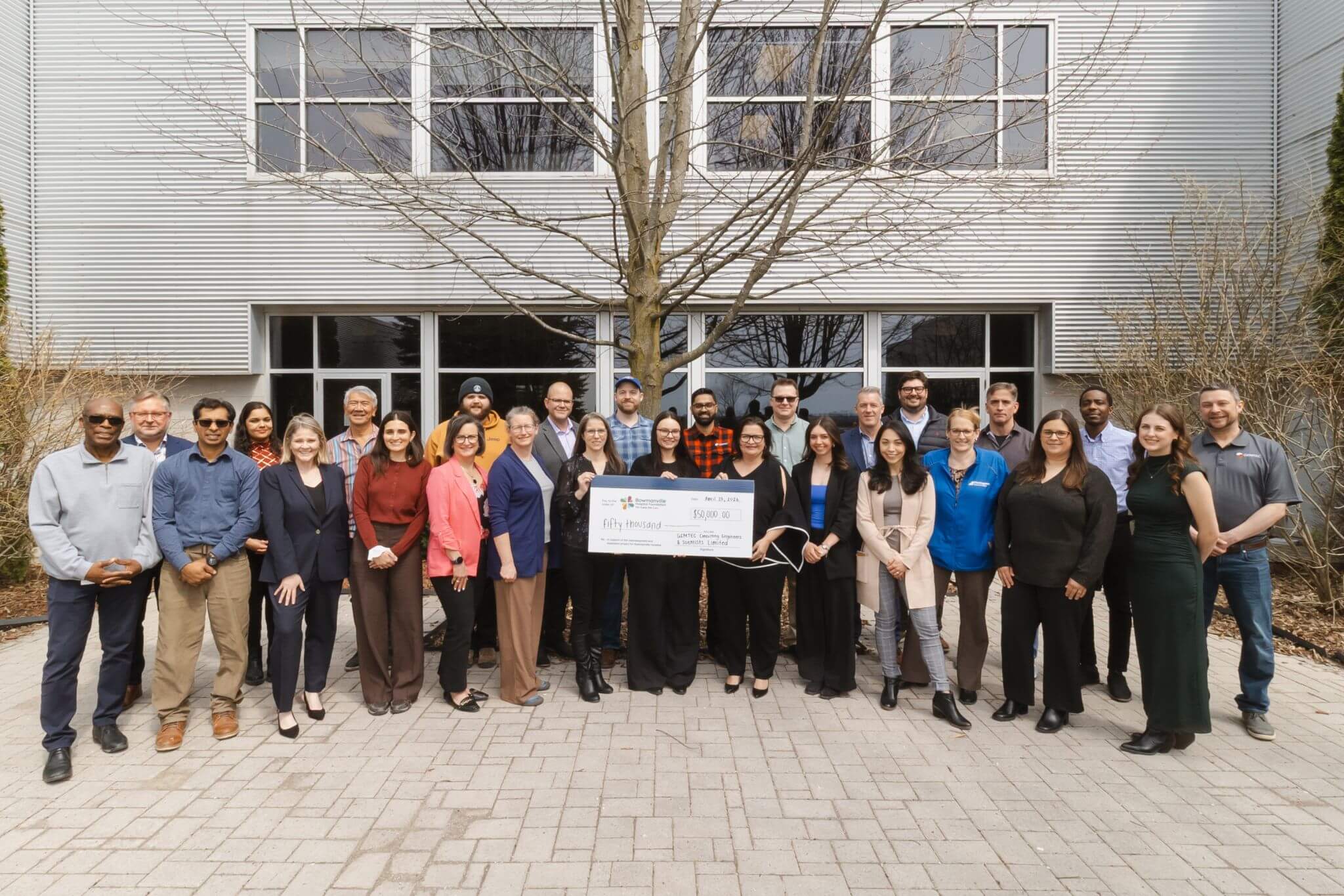 A large group of people gathered outside with a cheque from GEMTEC to the Bowmanville Hospital Foundation.