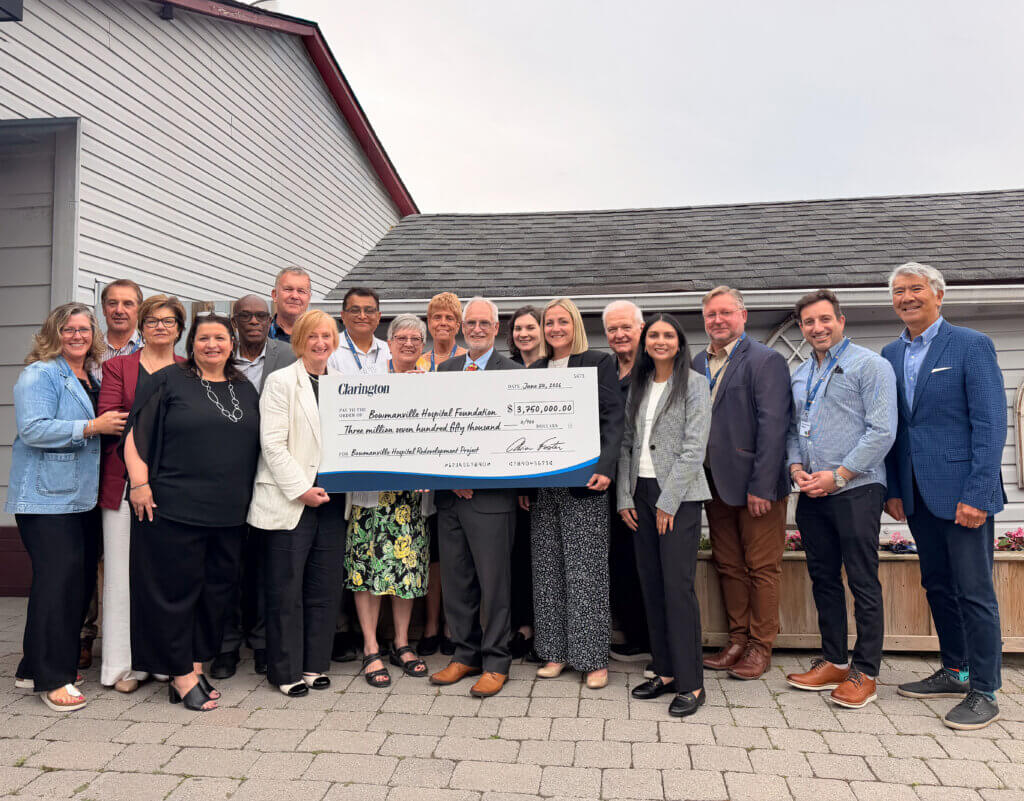 A large group of Foundation, Lakeridge Health and municipal leaders gathered outside a building with an oversized cheque from the Municipality of Clarington for $3.75M made out to the Bowmanville Hospital Foundation.