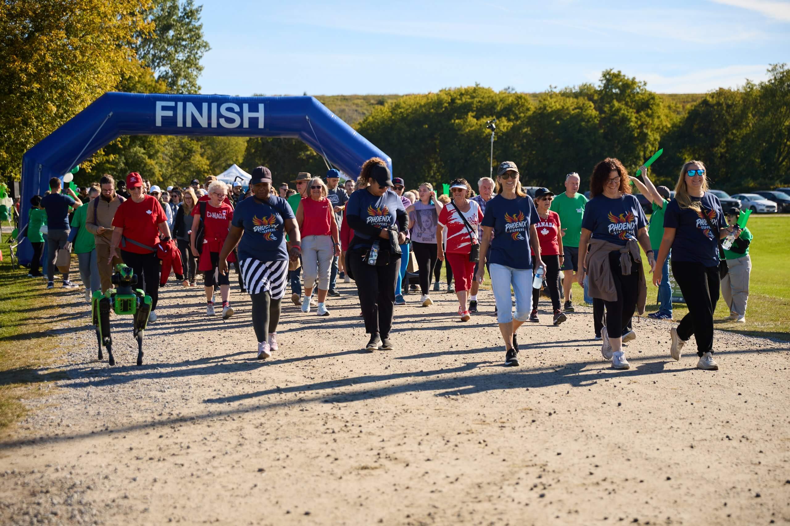 A large group of participants walking from the starting line on a gravel path.