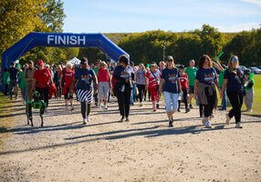 A large group of participants walking from the starting line on a gravel path.